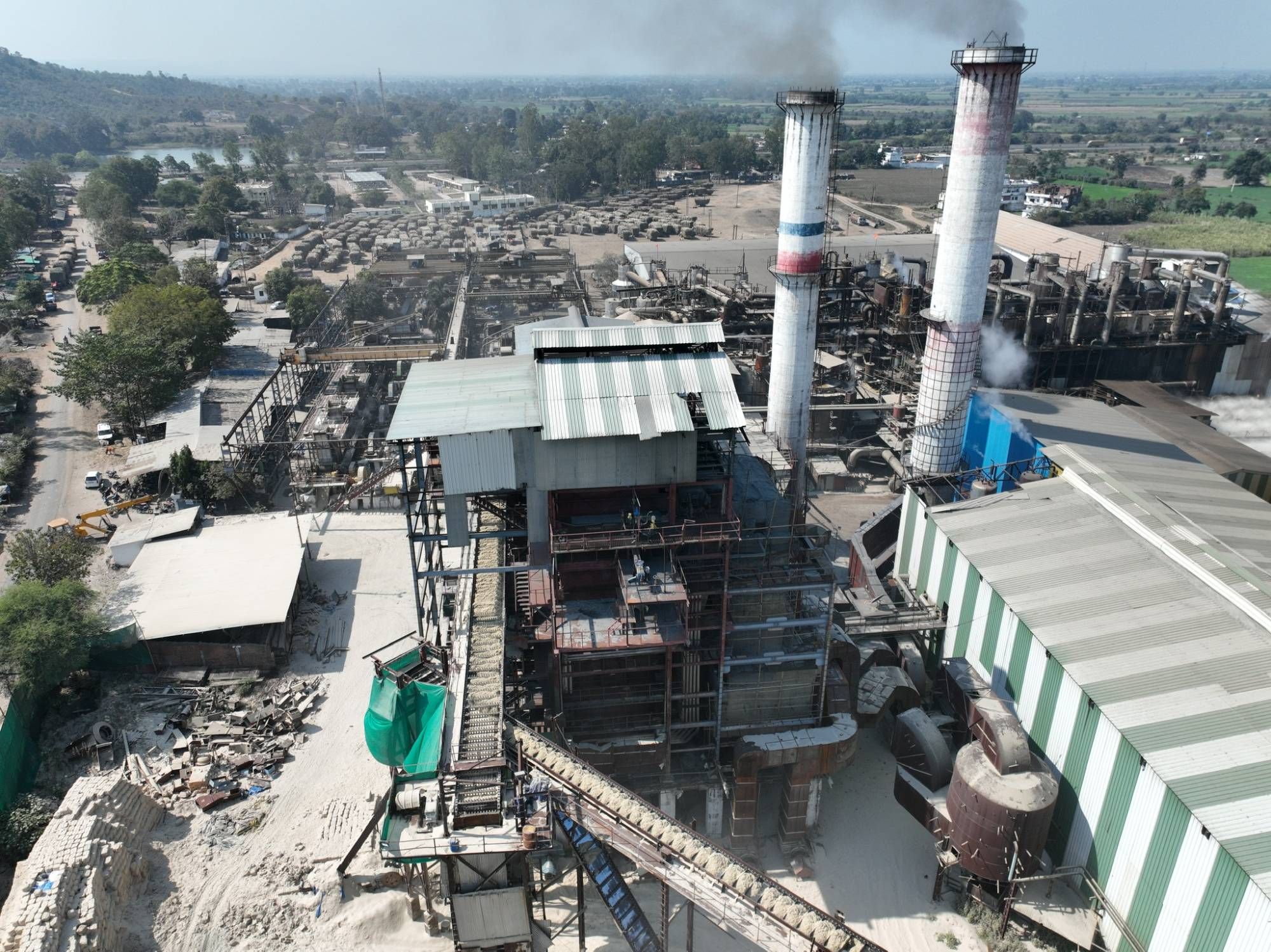 The sugar mill at Bachai under steam, the bagasse conveyor running and the cane yard behind it